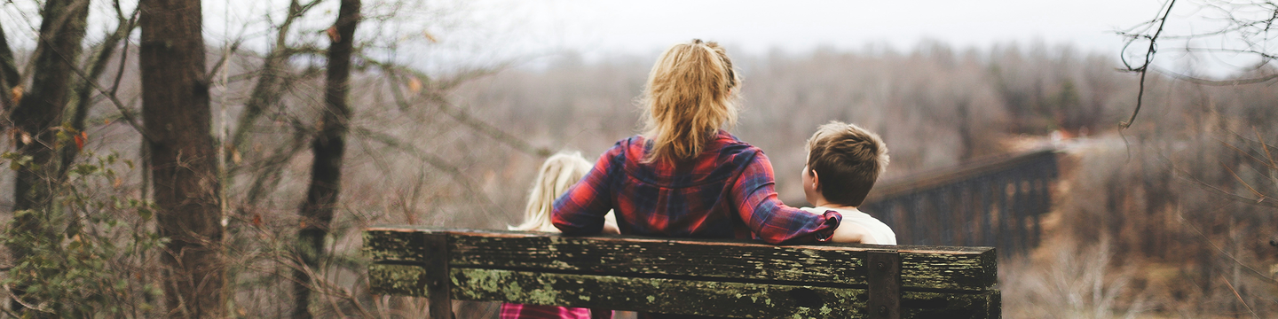 Autumnal woman and children sitting on seat looking out.png
